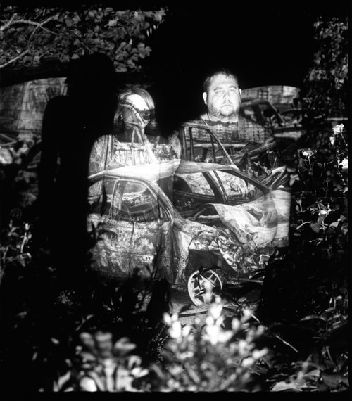 ARTEM AND NADIA WITH A PROJECTION OF THE SHOT CARS IN BUCHA (MYKOLAIV, 2023) by Sergey Melnitchenko