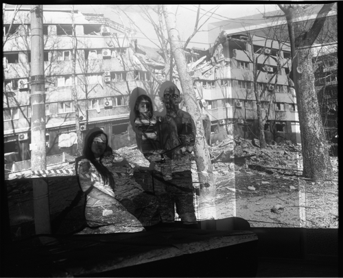 VIACHESLAV, MARIIA, ARTEM AND MAIIA WITH A PROJECTION OF THE BOMBED-OUT INGUL HOTEL IN MYKOLAIV (IVANO-FRANKIVSK, 2024) by Sergey Melnitchenko