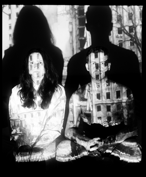 MARYNA AND SERHII WITH A PROJECTION OF THE MYKOLAIV REGIONAL STATE ADMINISTRATION BUILDING BOMBED BY A RUSSIAN MISSILE (IVANO-FRANKIVSK, 2023) by Sergey Melnitchenko